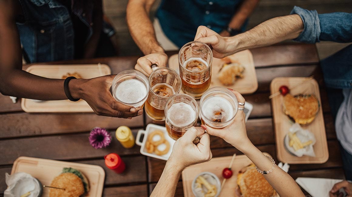 people around table toasting glasses of beer